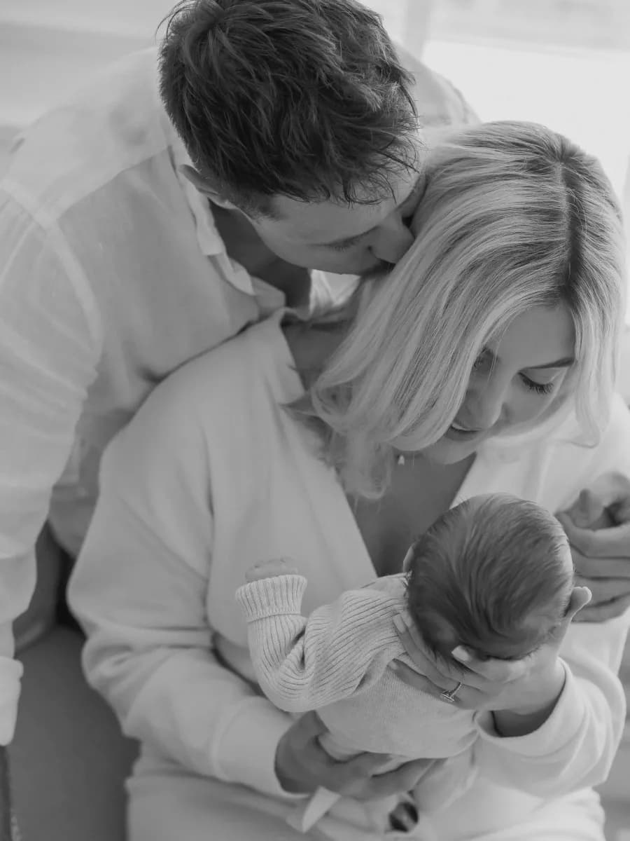 A man and woman holding a small child between them, all in light-coloured clothing, photographed from above in black and white