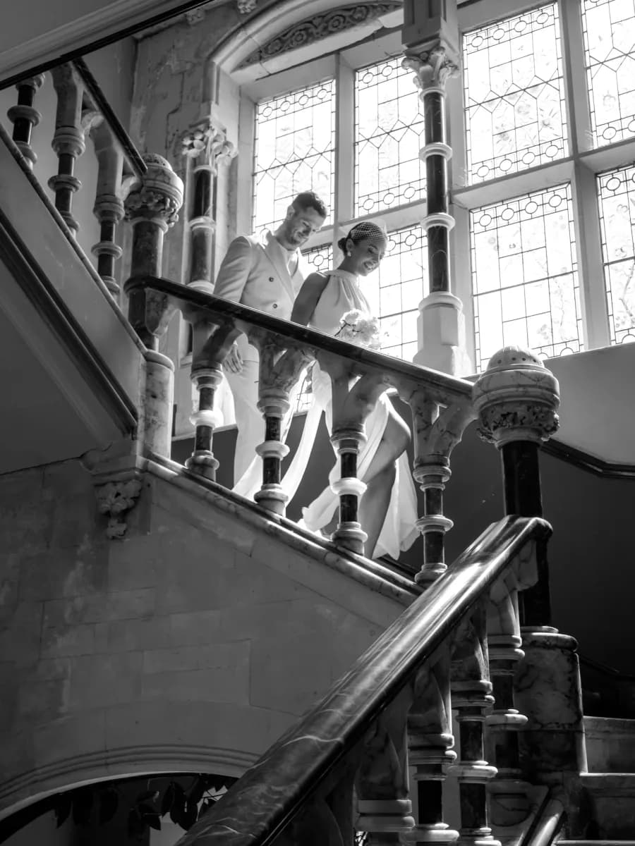 A woman and child descending a staircase with large windows behind them, photographed from below in black and white